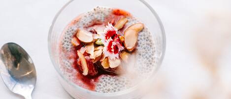 A bowl of dessert with a spoon beside it on a white surface.