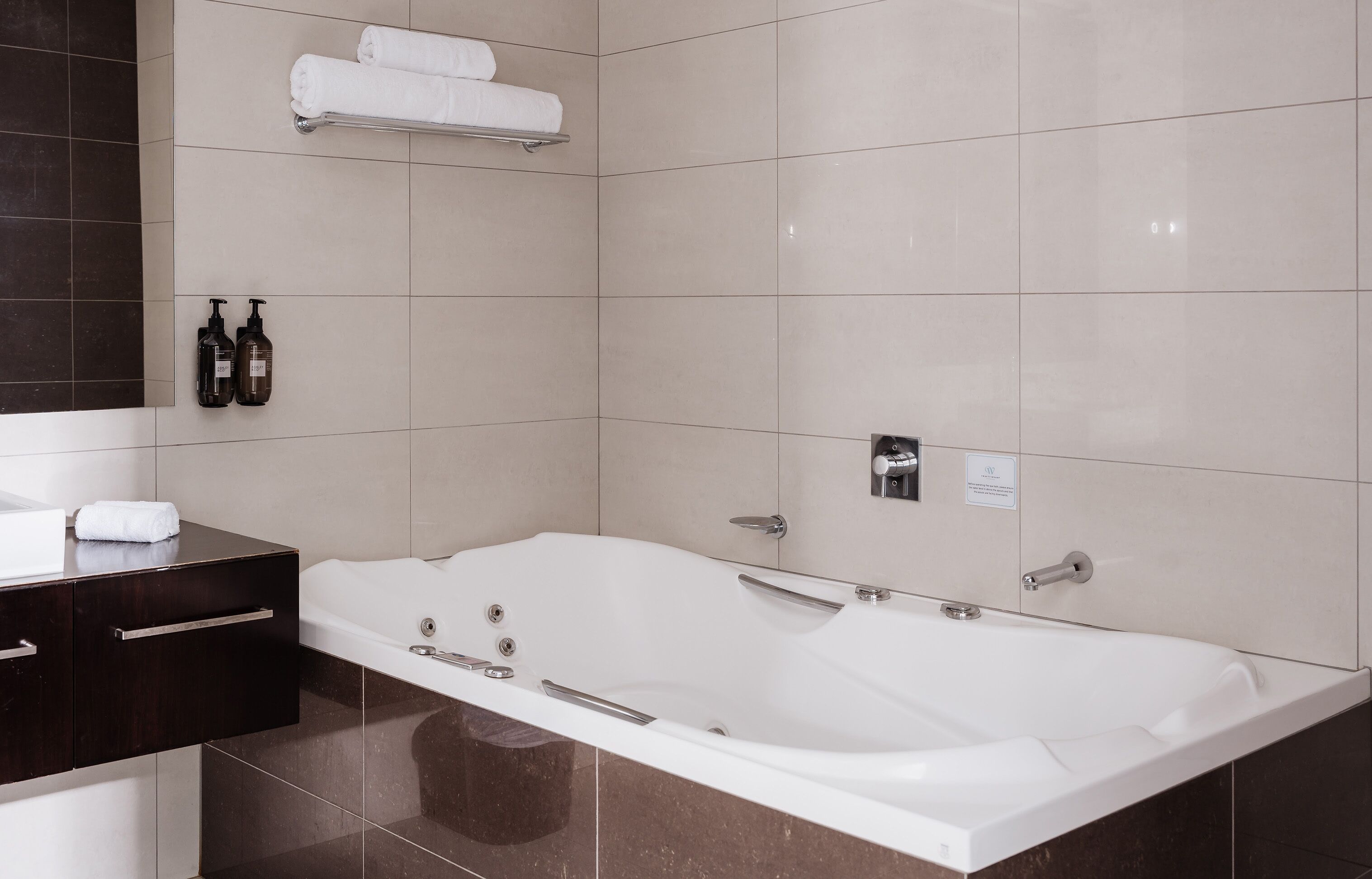 Une salle de bain moderne avec une grande baignoire, un meuble-lavabo en bois foncé et un porte-serviettes.