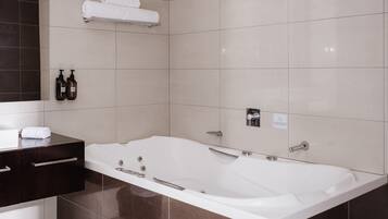 Une salle de bain moderne avec une grande baignoire, un meuble-lavabo en bois foncé et un porte-serviettes.