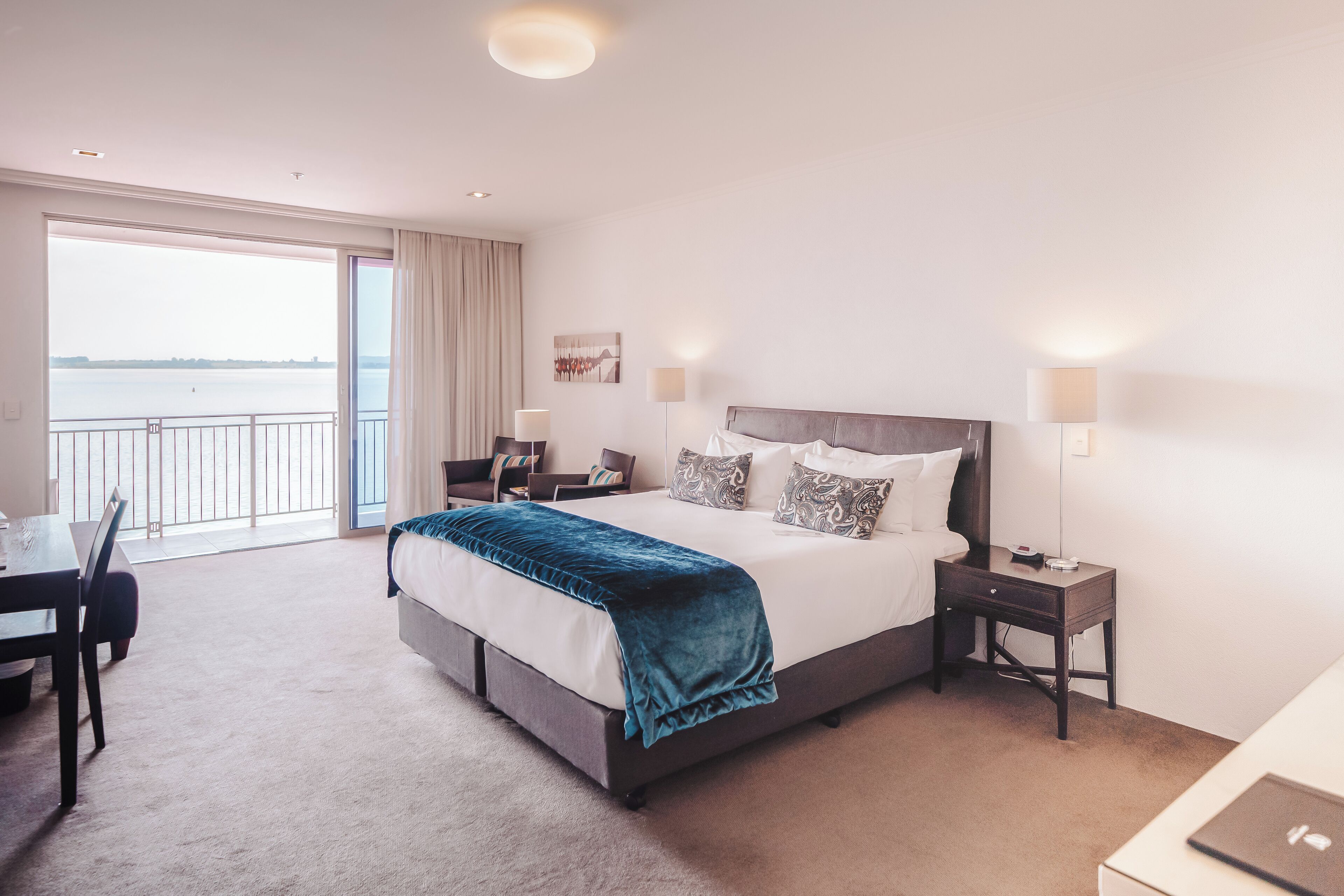 A hotel room with a large bed, a desk, and a view of the water.