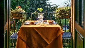 A balcony with a table set for two, featuring a tablecloth, plates, glasses, and a candle. - Locanda dello Spuntino (Grottaferrata)