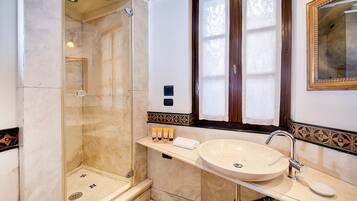 Une salle de bain dotée d’une douche à parois de verre, d’un lavabo avec un meuble-vasque et d’un miroir encadré.