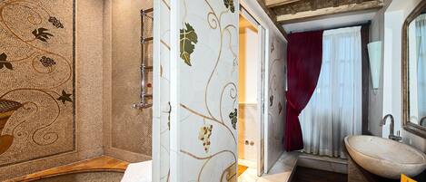 Un bagno con parete in mosaico, una panca in legno, un lavandino e uno specchio.