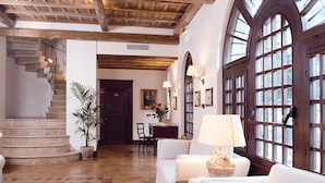 A spacious hallway with a stone floor, a staircase, and a seating area with a table and chairs. - Locanda dello Spuntino (Grottaferrata)