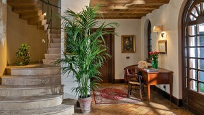 A staircase with a potted plant, a wooden desk with a vase, and a dining area with chairs. - Locanda dello Spuntino (Grottaferrata)