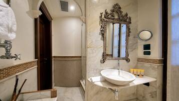 Une salle de bain avec un lavabo en marbre, un grand miroir et un espace douche.