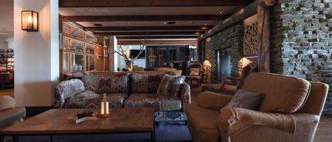 A cozy lounge area with a patterned sofa, a wooden coffee table, and a stone wall.