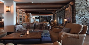 A cozy lounge area with a patterned sofa, a wooden coffee table, and a stone wall. - Lapland Hotels Olos (Muonio)