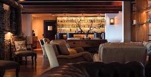A cozy living room with a bar area in the background, featuring a variety of seating options and a fireplace. - Lapland Hotels Olos (Muonio)