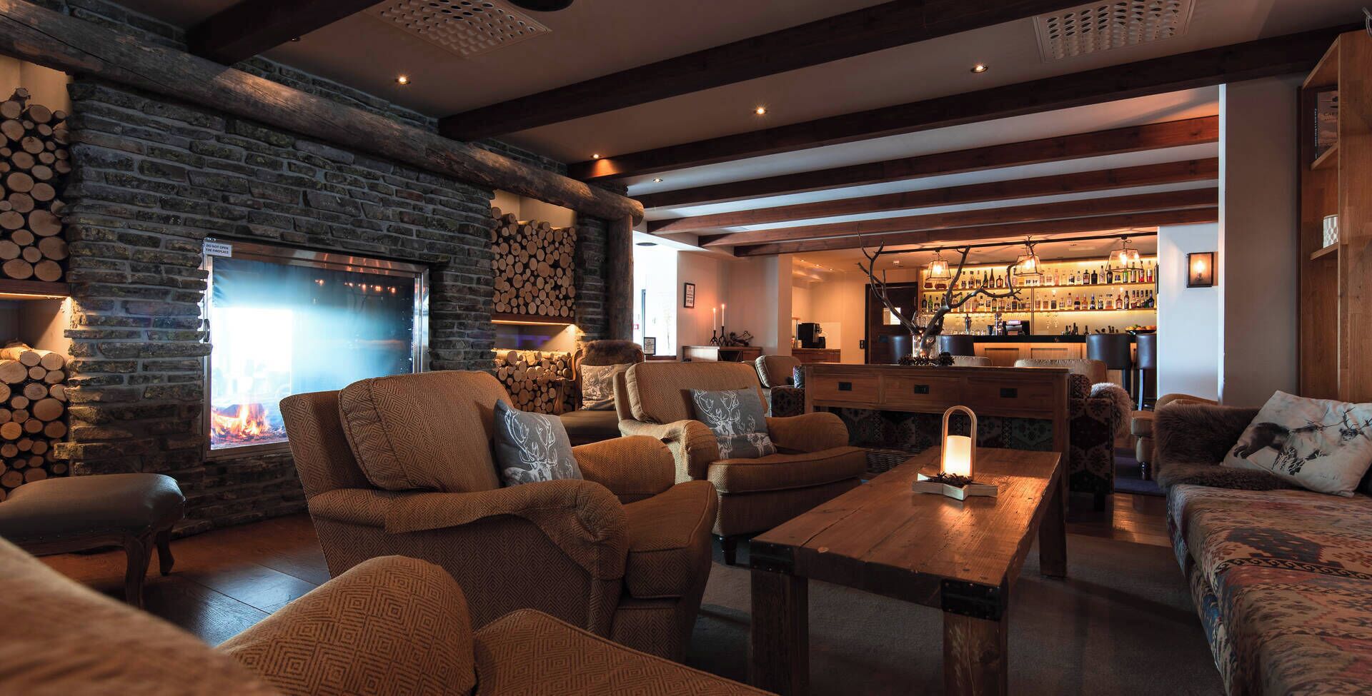 A cozy interior with a stone fireplace, wooden furniture, and a bar area.