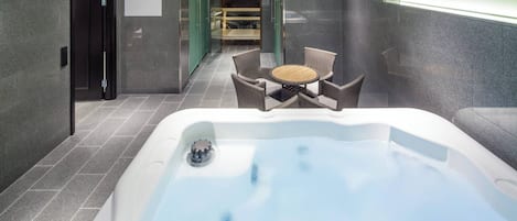 A spa area with a hot tub, wicker chairs, and a glass-enclosed seating area.