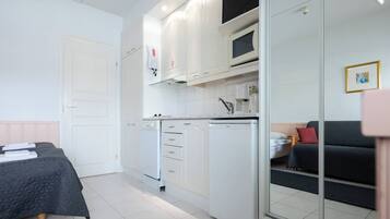 A compact room with a bed, kitchenette, and a seating area.