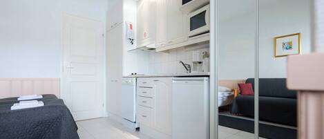 Ein kleines Zimmer mit Bett, Küchenzeile und Sitzecke.