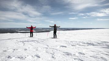 Two people skiing on a snowy mountain with a clear sky.