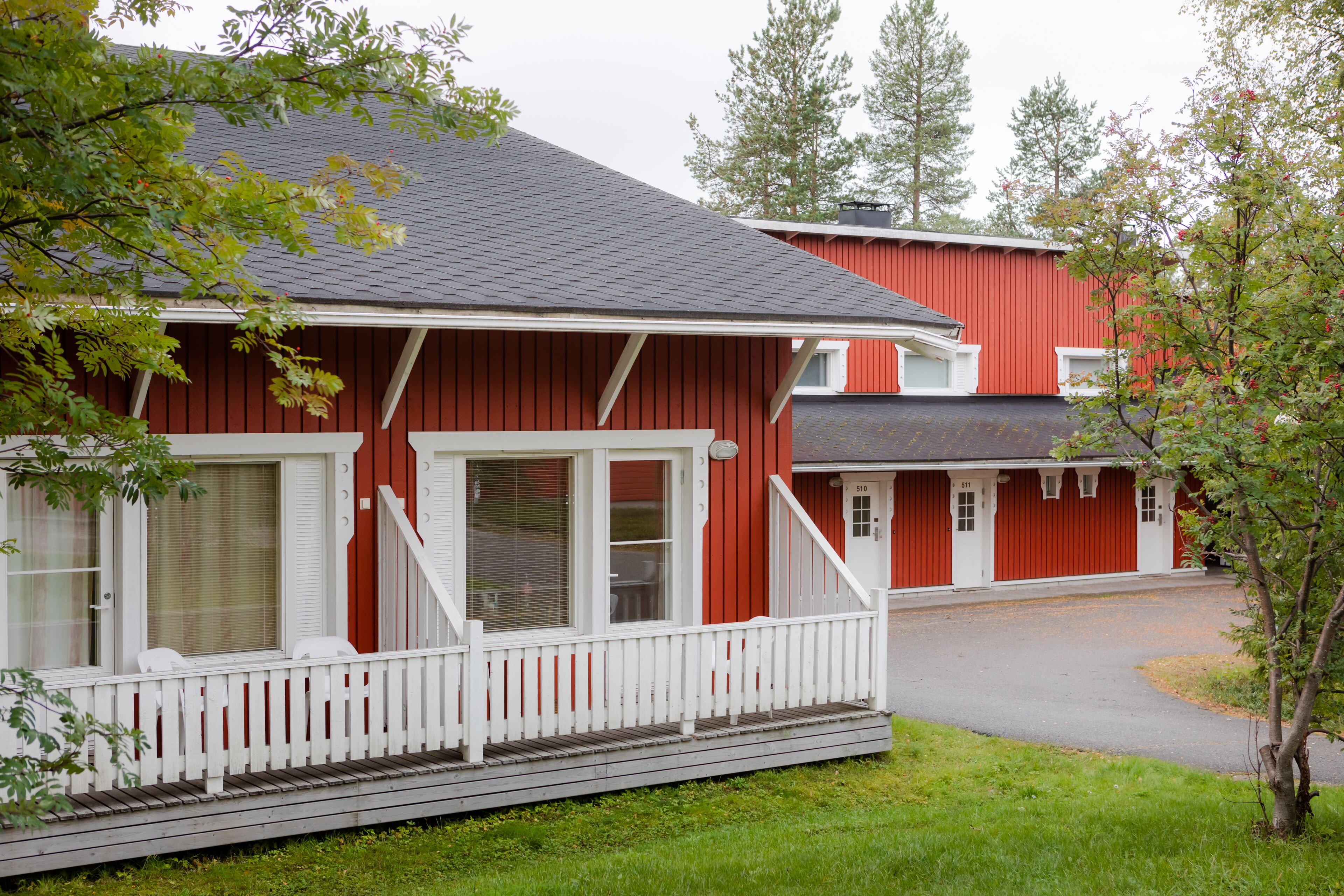 A red building with a white porch and a grey roof.