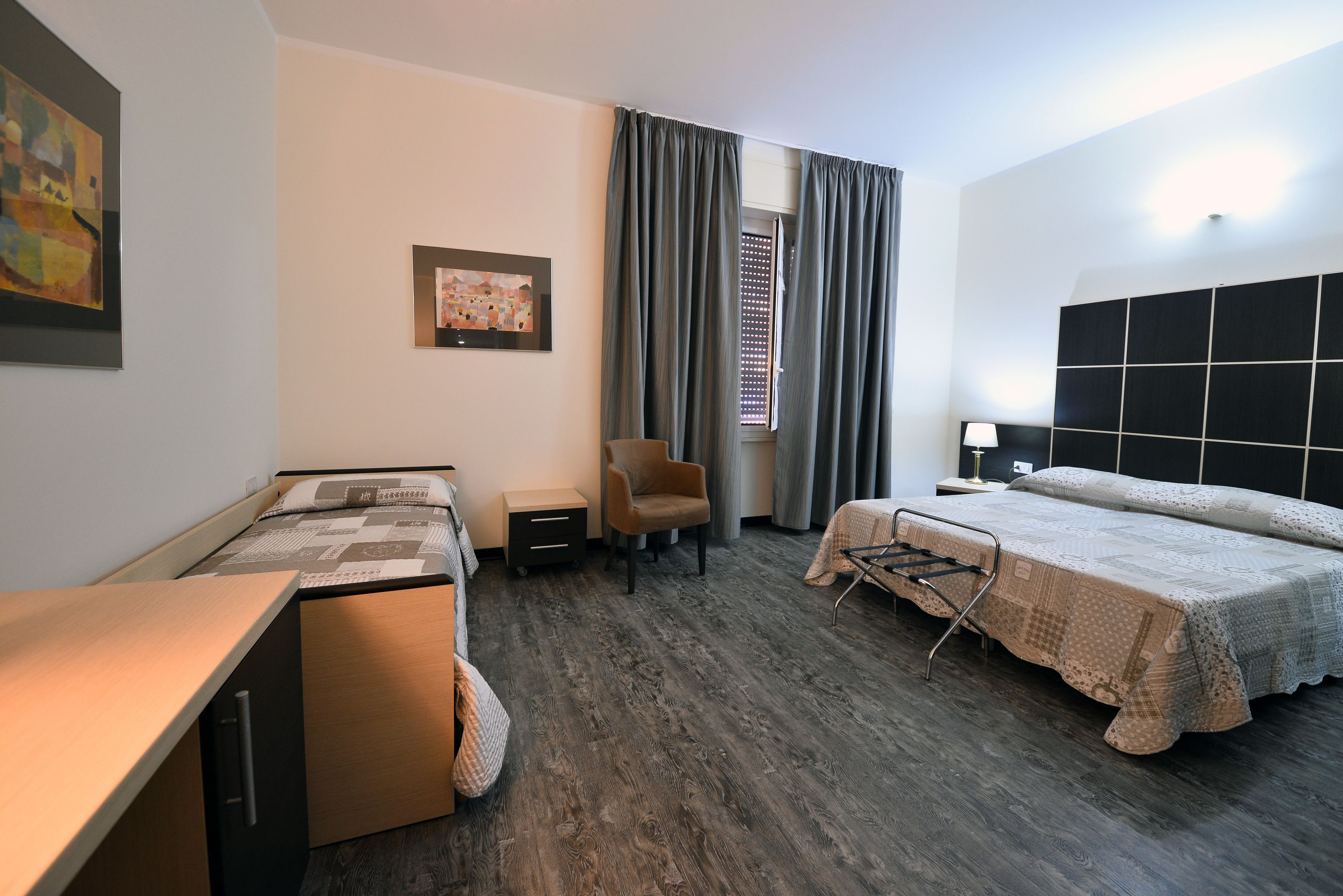 A hotel room with a bed, a desk, a chair, and a small table.