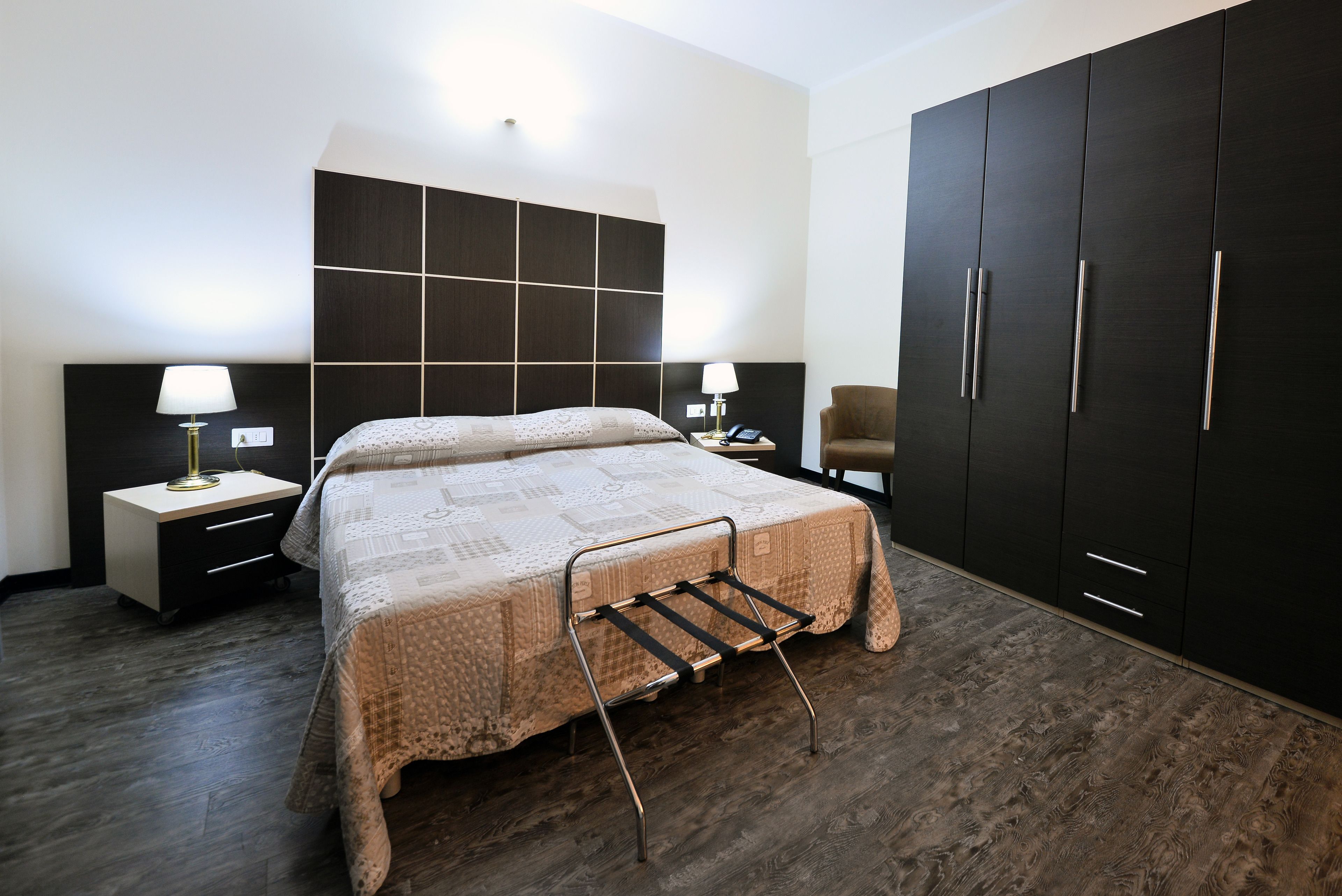 Ein Hotelzimmer mit Bett, Nachttischen, einem Schrank und einem Sessel.
