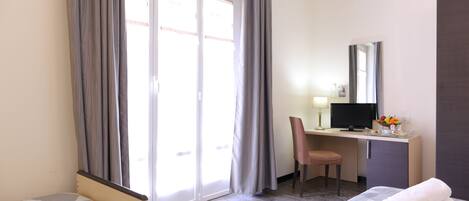 Ein Hotelzimmer mit Bett, Schreibtisch inklusive Computer, einem Sessel und einem Fernseher.