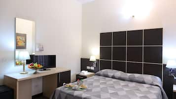 Habitación de hotel con cama, escritorio y televisor. Hay una bandeja con alimentos para el desayuno sobre la cama.