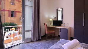 A hotel room with a balcony, a desk with a chair, a bed, and a wardrobe. - Hotel Ferrari (Chiavari)