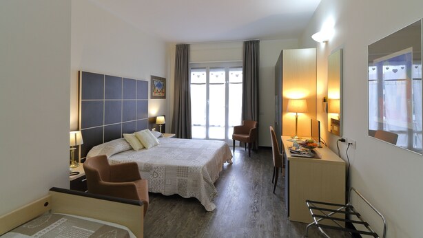 A hotel room with a bed, two chairs, a desk, and a large mirror. - Hotel Ferrari (Chiavari)
