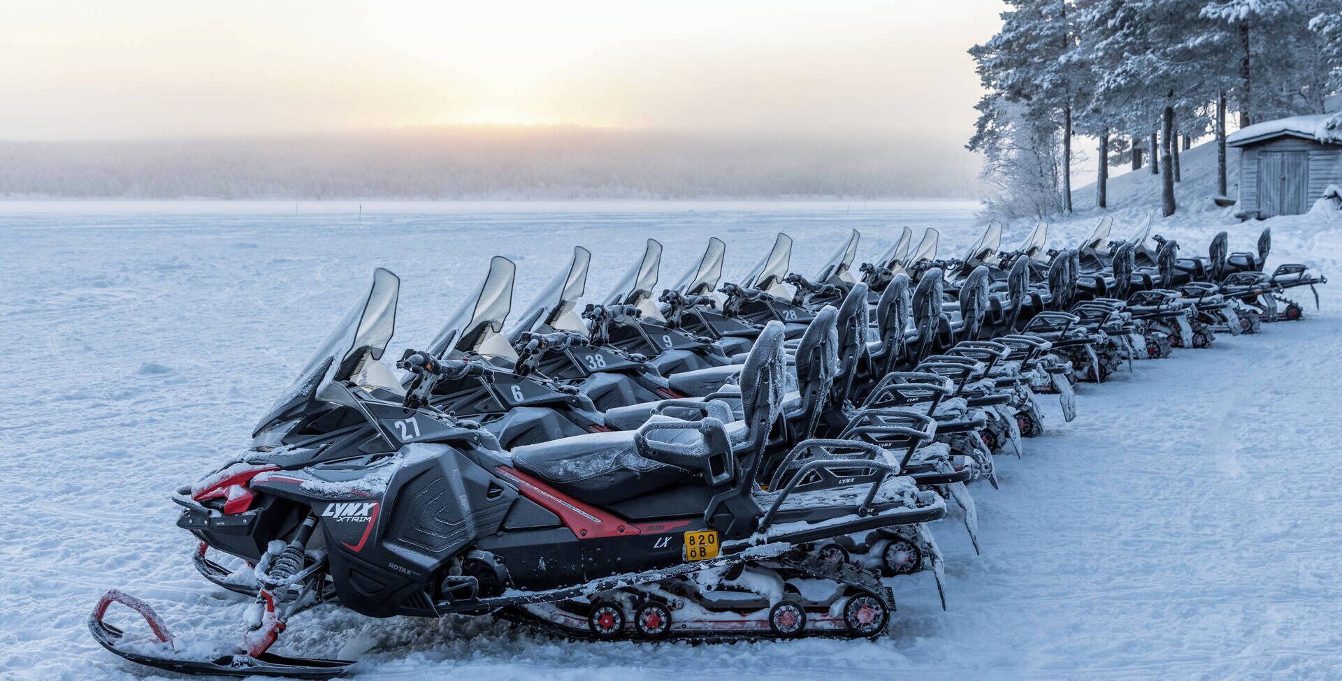 A row of snowmobiles parked in a snowy field.