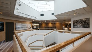 A modern interior with a central open space, wooden railings, and artwork on the walls. - Lapland Hotels Hetta (Enontekio)