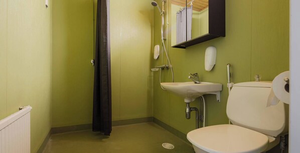 A small bathroom with a toilet, sink, and shower.