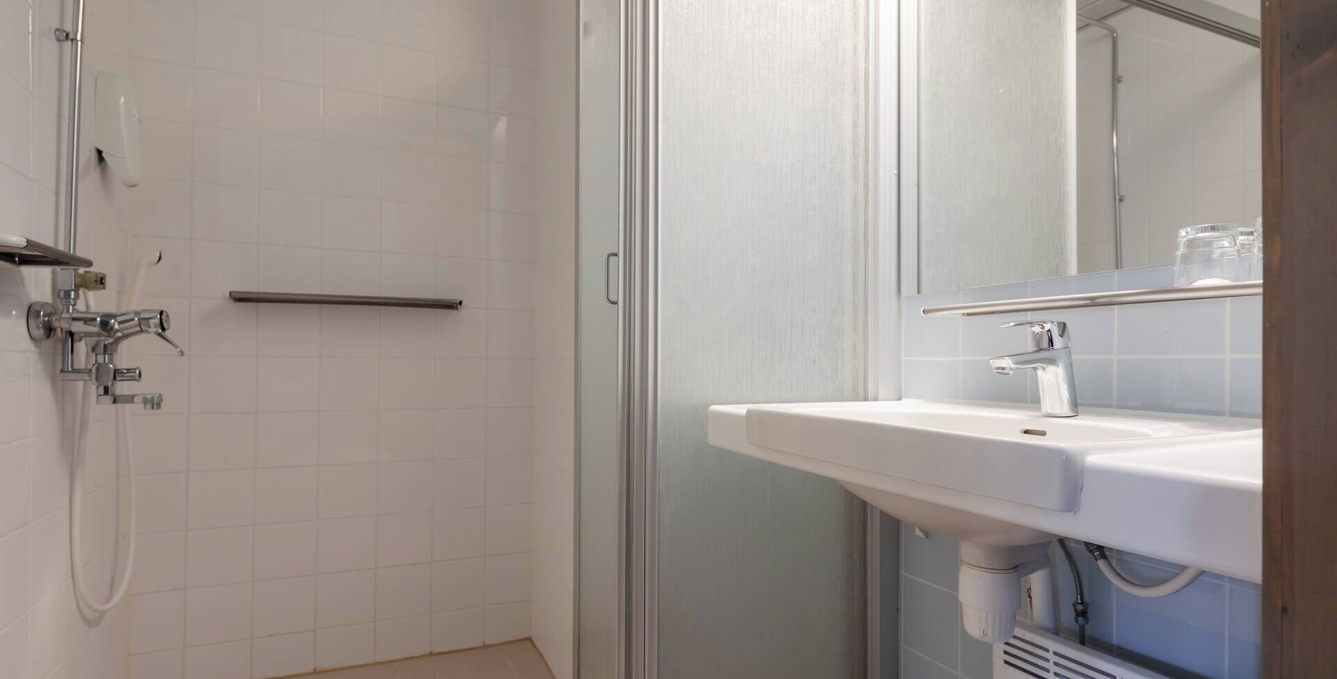A bathroom with a shower, a sink, and a mirror.