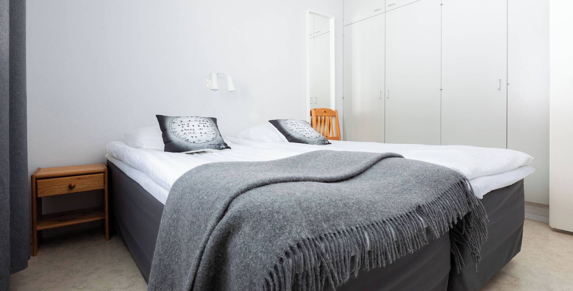A bedroom with a bed, bedside tables, a wardrobe, and a mirror.