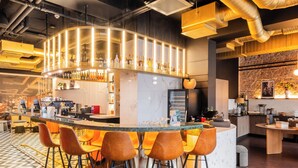 A modern bar area with a curved counter, bar stools, and a mix of wooden and marble flooring. - TRIBE Riga City Centre Hotel - Renovated 2026 (Riga)