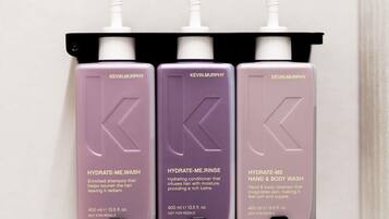 Tre flasker Kevin Murphy hudplejeprodukter står på en sort hylde.