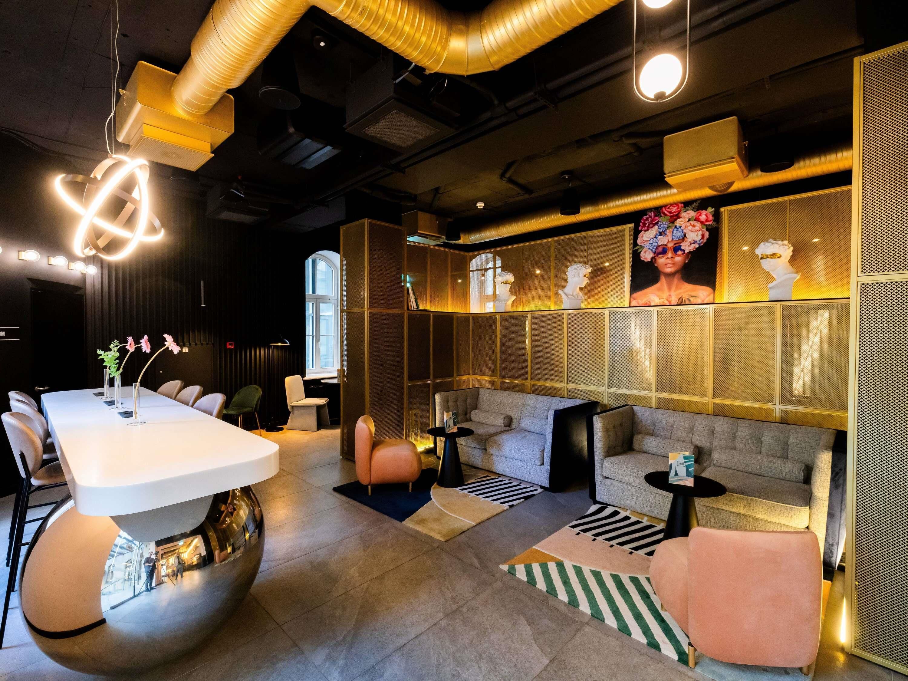 A modern lounge area with a white table, sofas, and a decorative wall with busts.