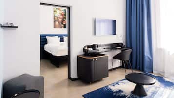 A modern hotel room with a bed, desk, chair, and a painting on the wall.