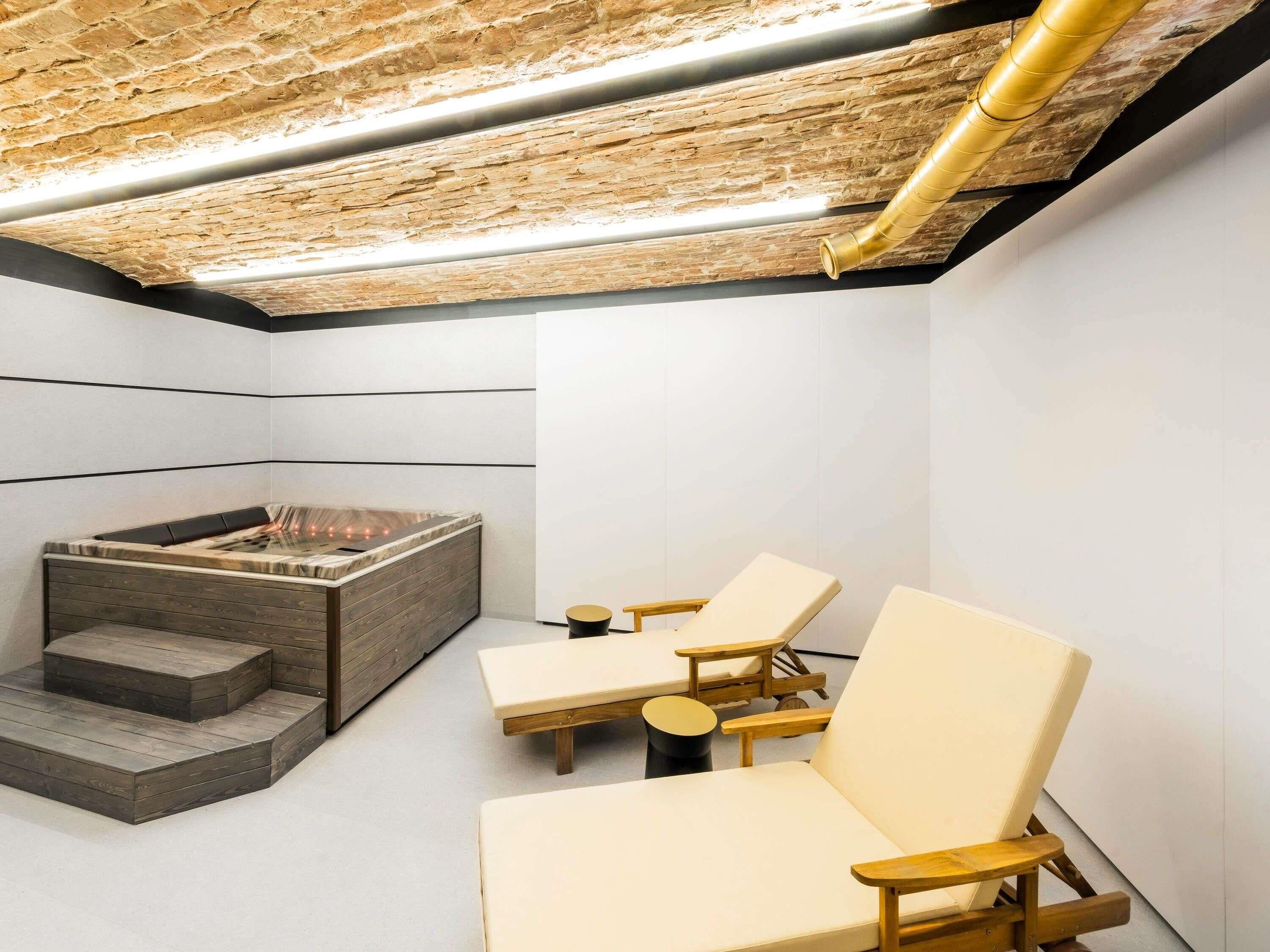 Um spa moderno com banheira de hidromassagem, escadas de madeira e duas cadeiras de descanso.