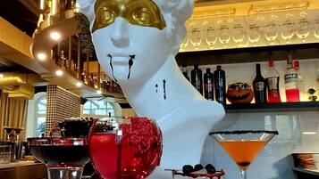 A bar area with a white bust sculpture, various bottles, and three different drinks on the counter.