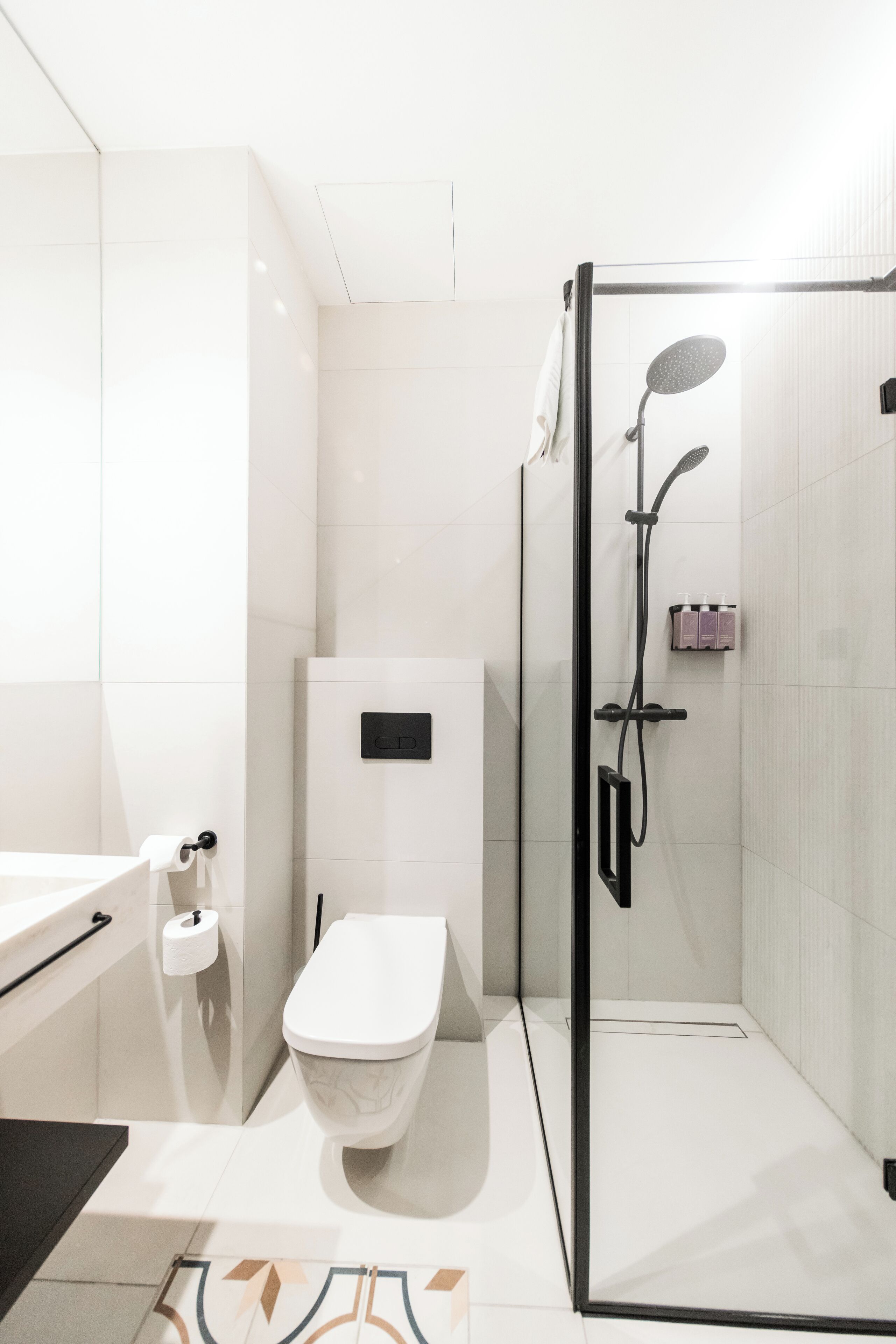 A modern bathroom with a glass-enclosed shower, a toilet, and a sink.