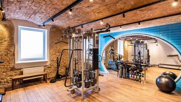 Une salle de sport avec un plafond en briques, un plancher en bois et divers appareils d’exercice.