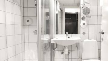 Une salle de bain moderne avec une douche à parois de verre, un lavabo blanc et des toilettes.