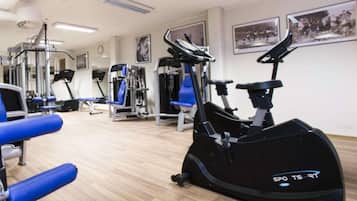 Un gimnasio con máquinas de cardio, equipo de levantamiento de pesas y sillas azules.
