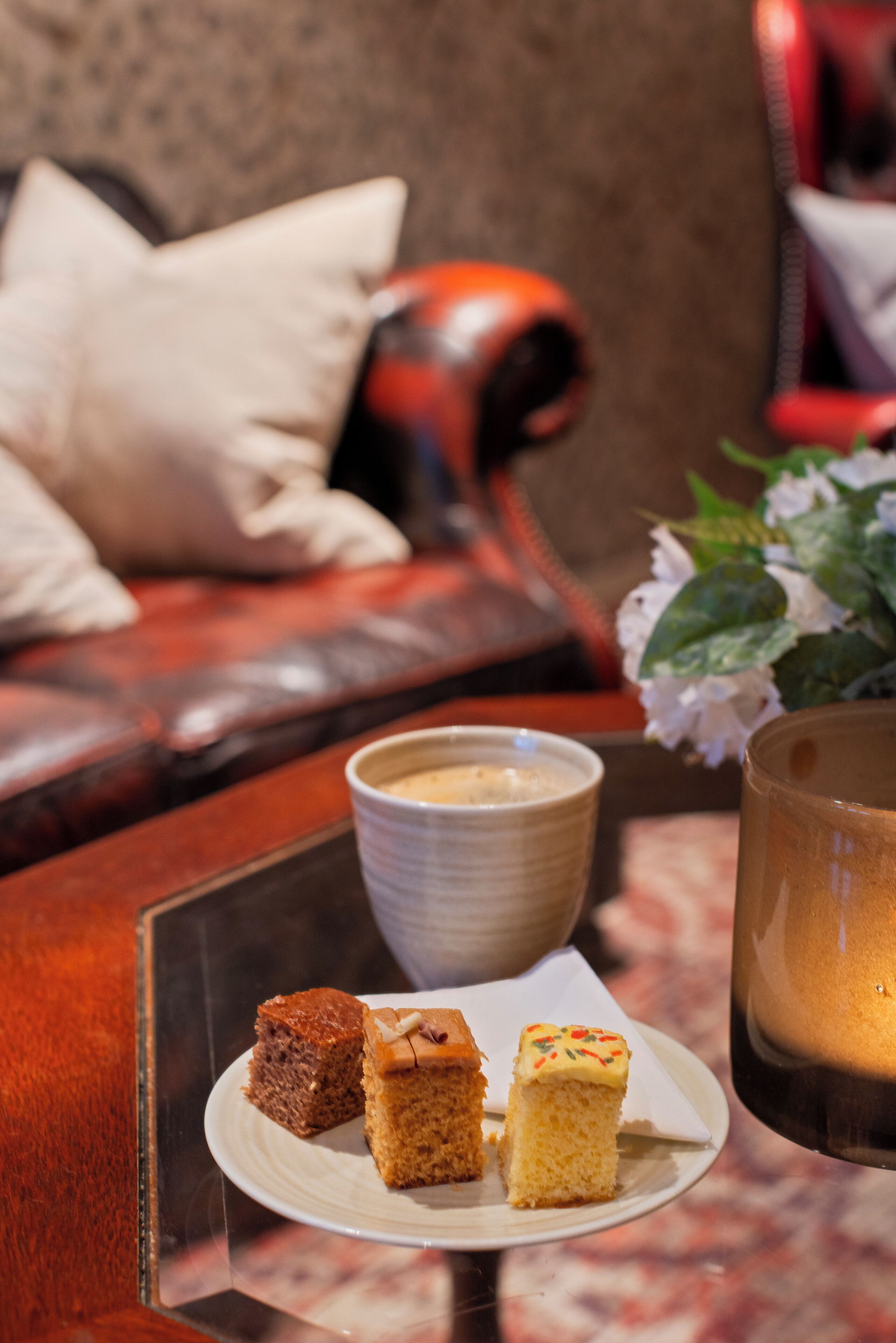 A table with a plate of desserts, a cup of coffee, and a candle.