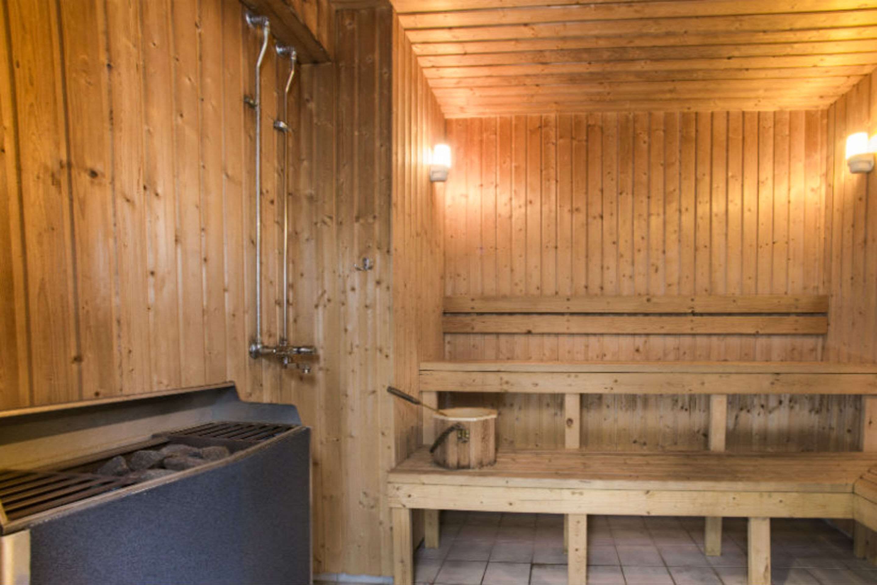 A wooden sauna with benches and a heating element.