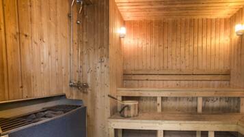 A wooden sauna with benches and a heating element.