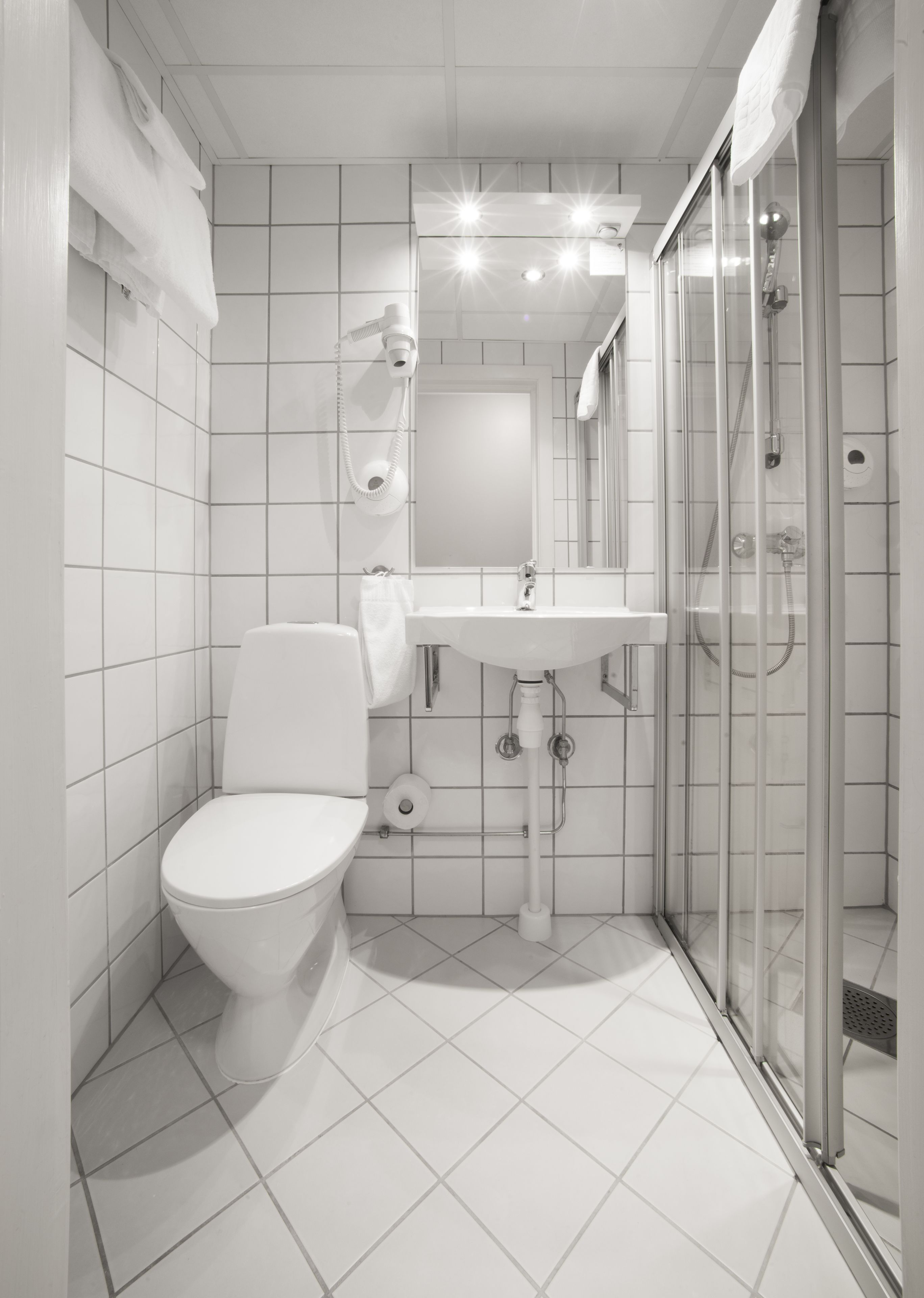 Ett modernt badrum med toalett, handfat och dusch med glasväggar.