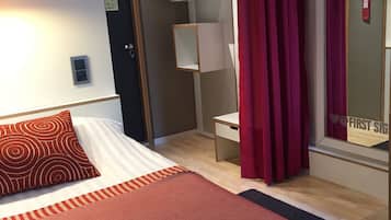 Una habitación de hotel moderna con una cama grande, un escritorio y un espejo.