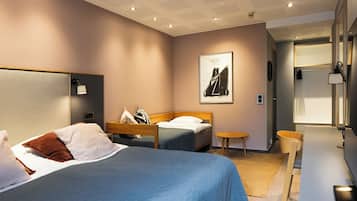 A hotel room with a large bed, a smaller bed, a desk, and a chair. There is a painting on the wall and a window with a view.