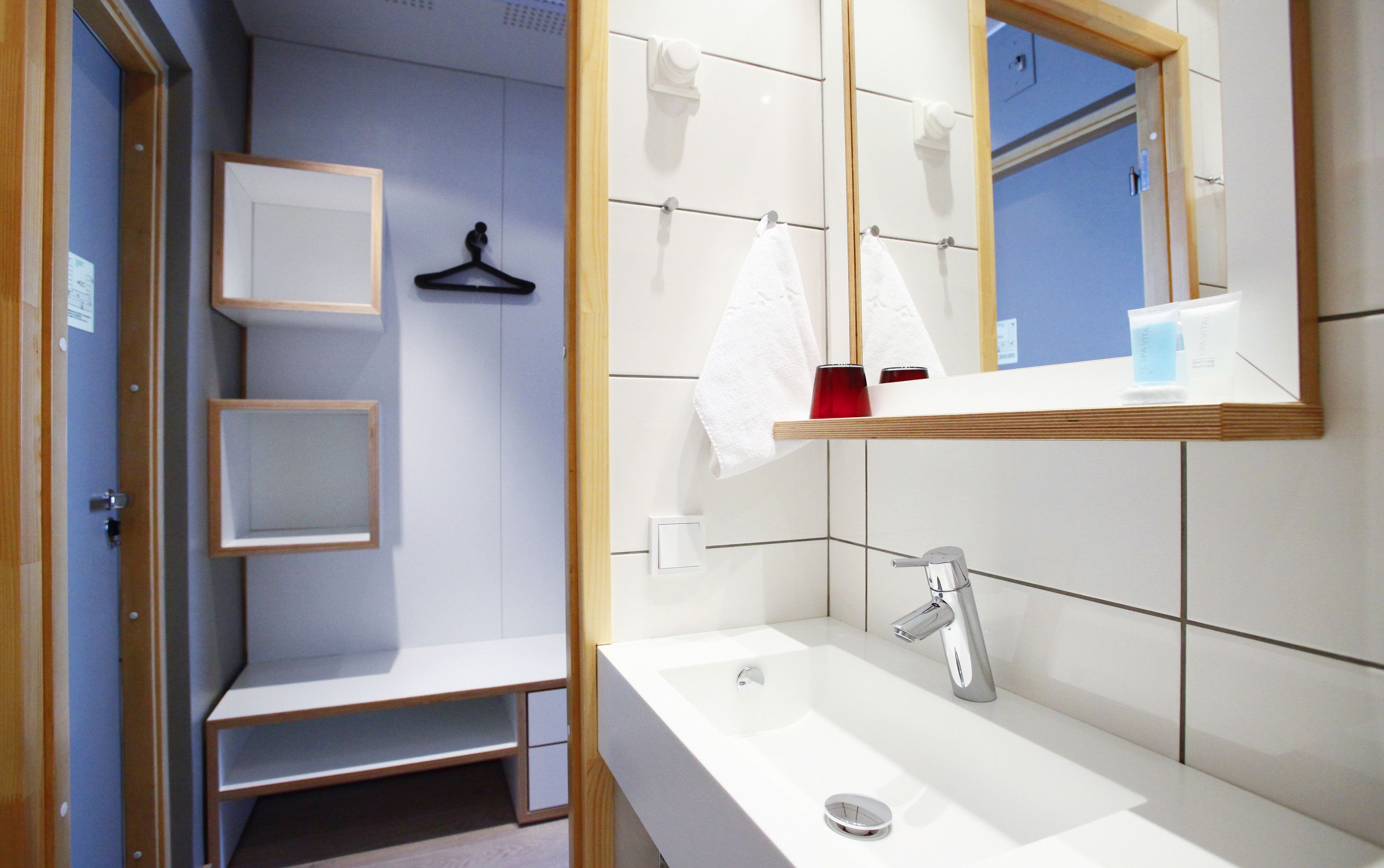Un baño moderno con un lavamanos blanco, un espejo y un perchero para toallas.