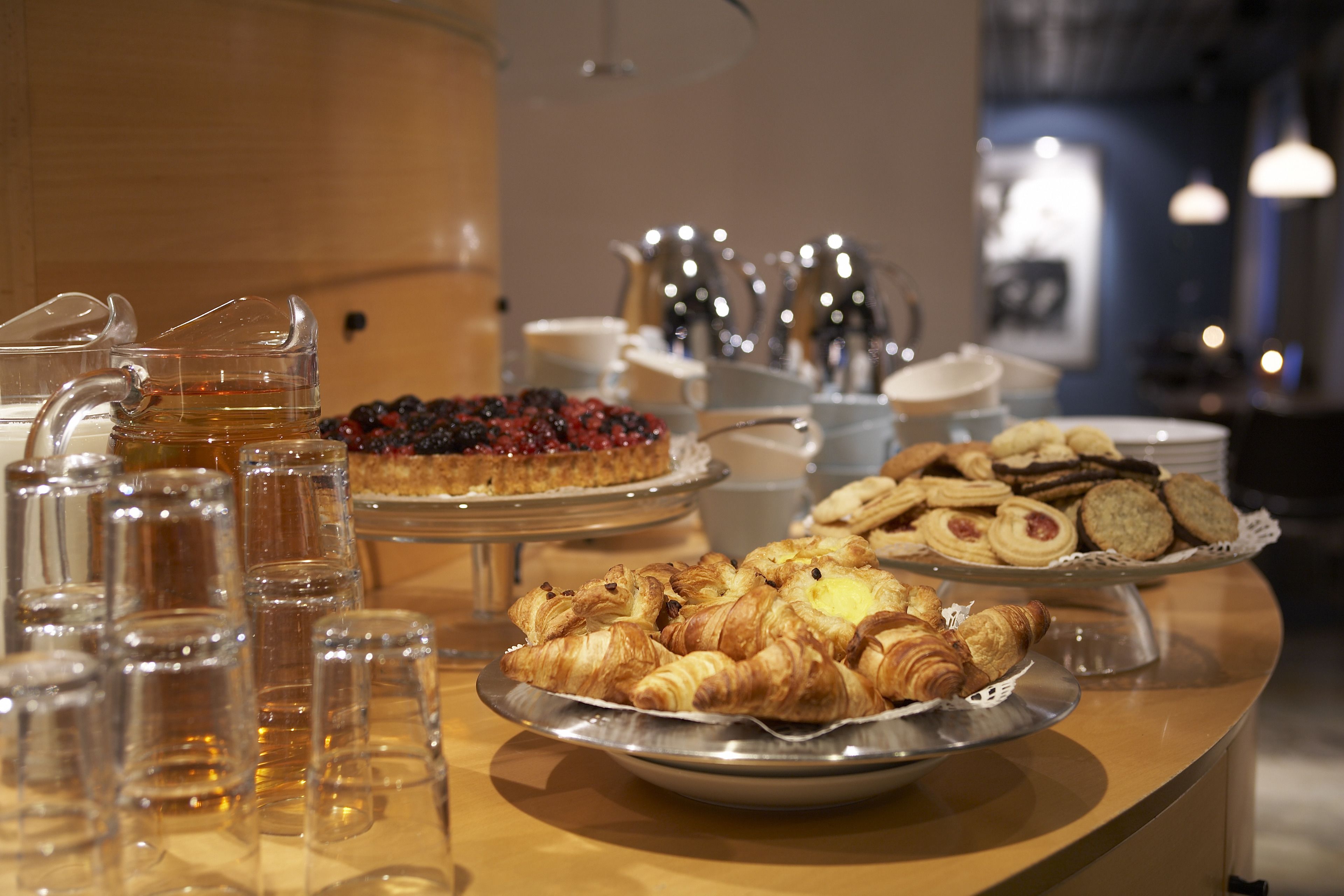 A buffet table with various pastries, a coffee station, and a fruit display.