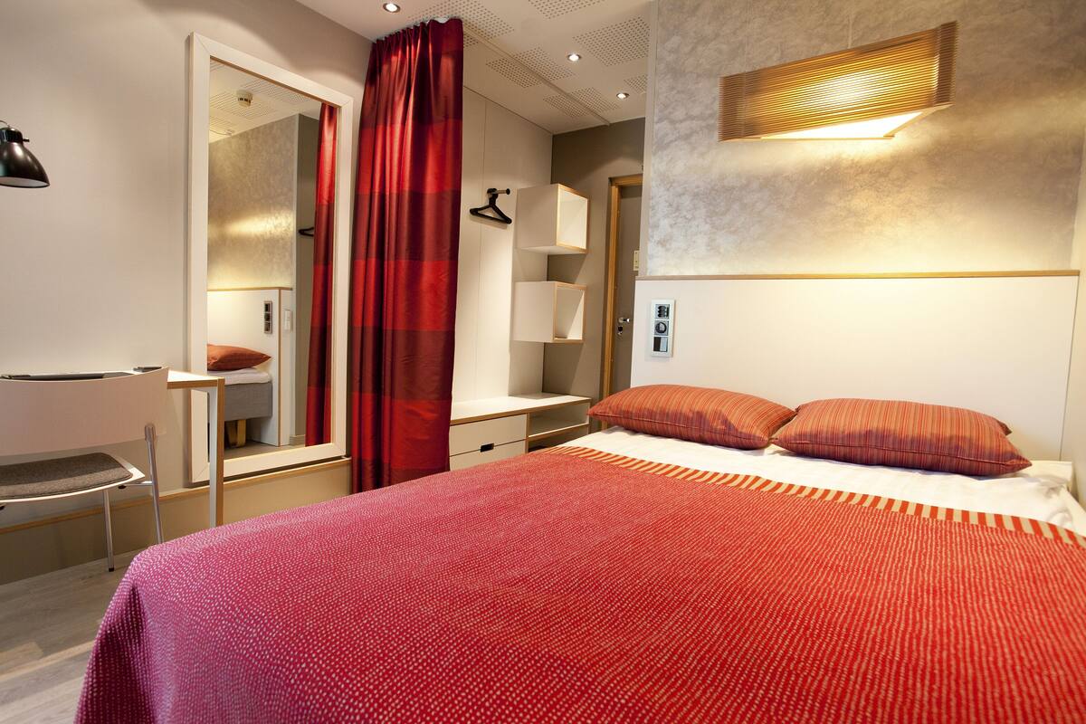 A modern bedroom with a large bed, a desk, and a mirror.