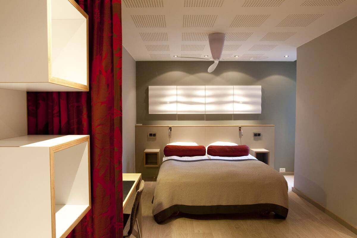 A modern bedroom with a bed, bedside tables, a mirror, and a ceiling fan.